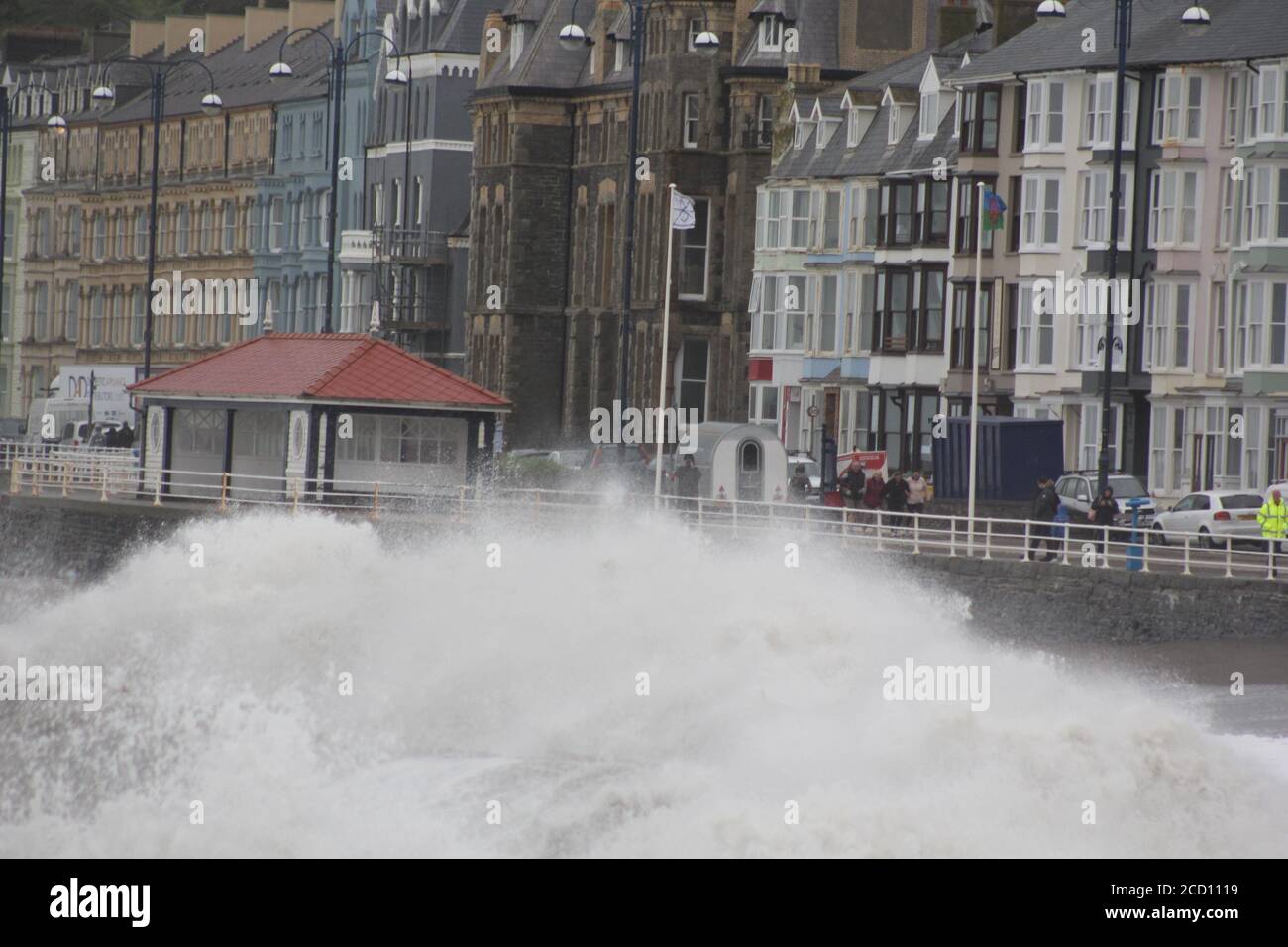 Aberystwyth Wales UK Weather 25 agosto 2020 : forti piogge e venti di Gale Force battter regioni costiere del Galles, forti venti guidare in enormi onde che sconfinano contro le difese marine di Aberystwyth. I vacanzieri coraggiosi venti di forza gale durante una passeggiata pomeridiana tempesta lungo la passeggiata, Credit: mike davies/Alamy Live News Foto Stock