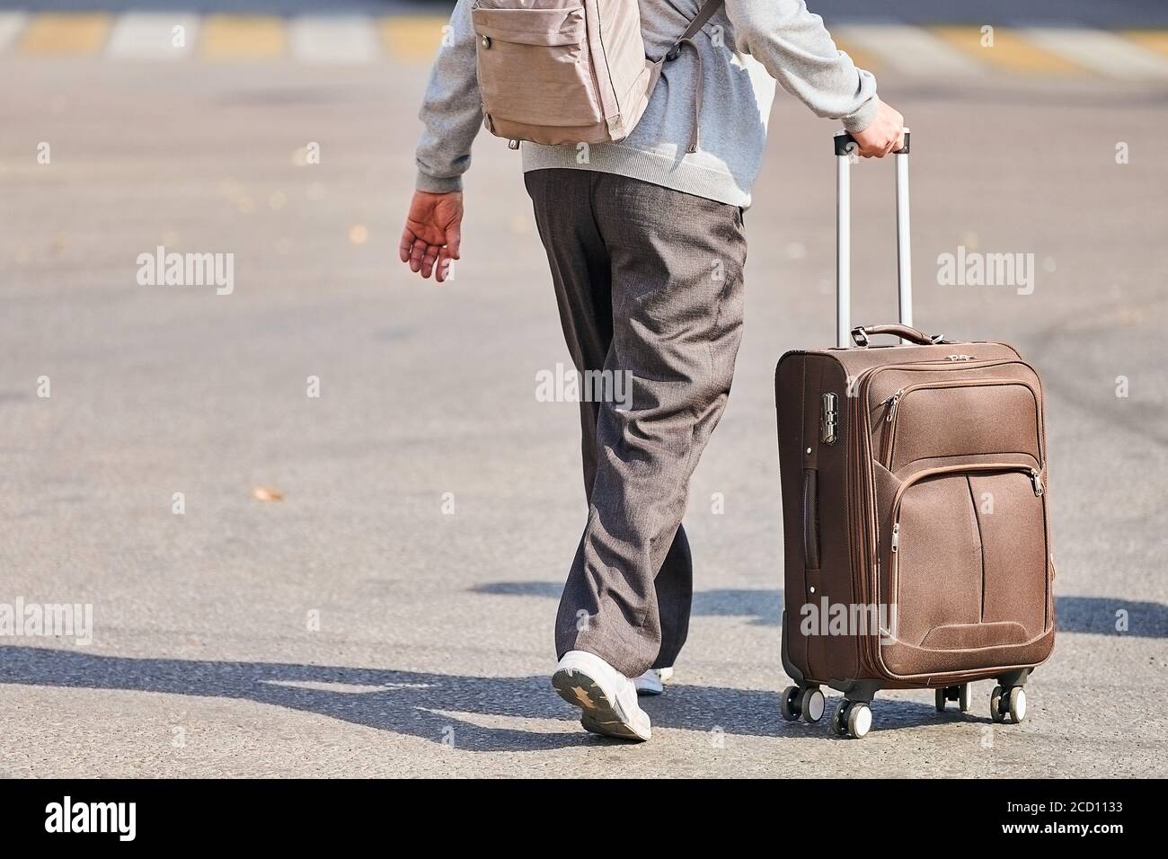 Uomo anziano con valigia su ruote. Uomo con bagaglio a mano in fondo alla  strada dall'aeroporto. Ritorno a casa dopo il viaggio. Effetto jet lag.  Vista posteriore Foto stock - Alamy