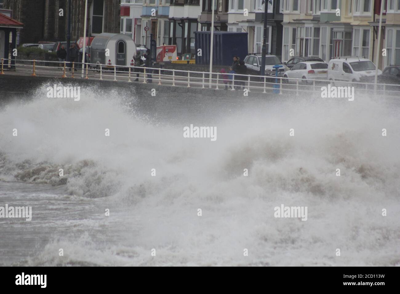 Aberystwyth Wales UK Weather 25 agosto 2020 : forti piogge e venti di Gale Force battter regioni costiere del Galles, forti venti guidare in enormi onde che sconfinano contro le difese marine di Aberystwyth. I vacanzieri coraggiosi venti di forza gale durante una passeggiata pomeridiana tempesta lungo la passeggiata, Credit: mike davies/Alamy Live News Foto Stock