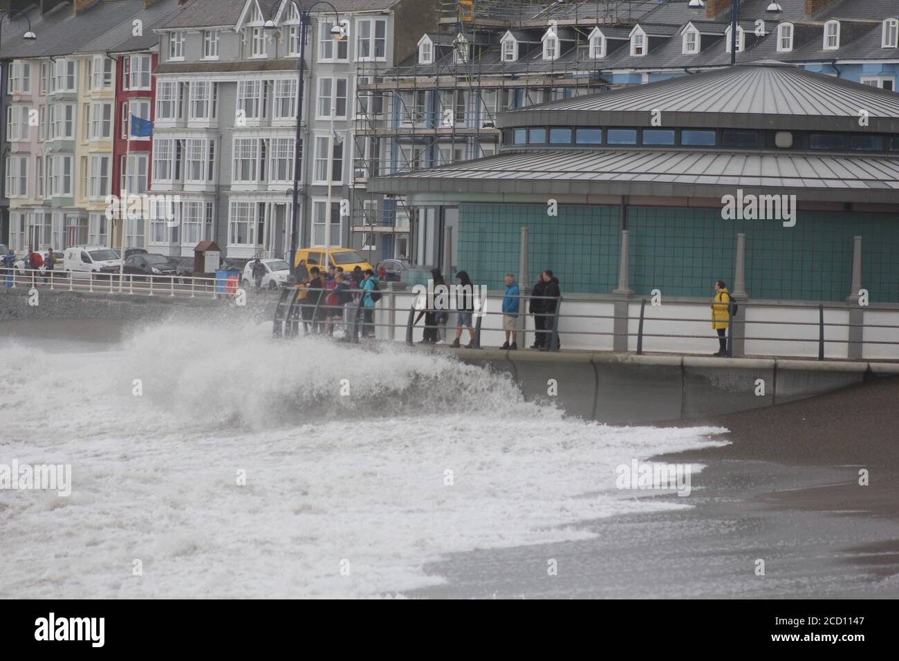 Aberystwyth Wales UK Weather 25 agosto 2020 : forti piogge e venti di Gale Force battter regioni costiere del Galles, forti venti guidare in enormi onde che sconfinano contro le difese marine di Aberystwyth. I vacanzieri coraggiosi venti di forza gale durante una passeggiata pomeridiana tempesta lungo la passeggiata, Credit: mike davies/Alamy Live News Foto Stock