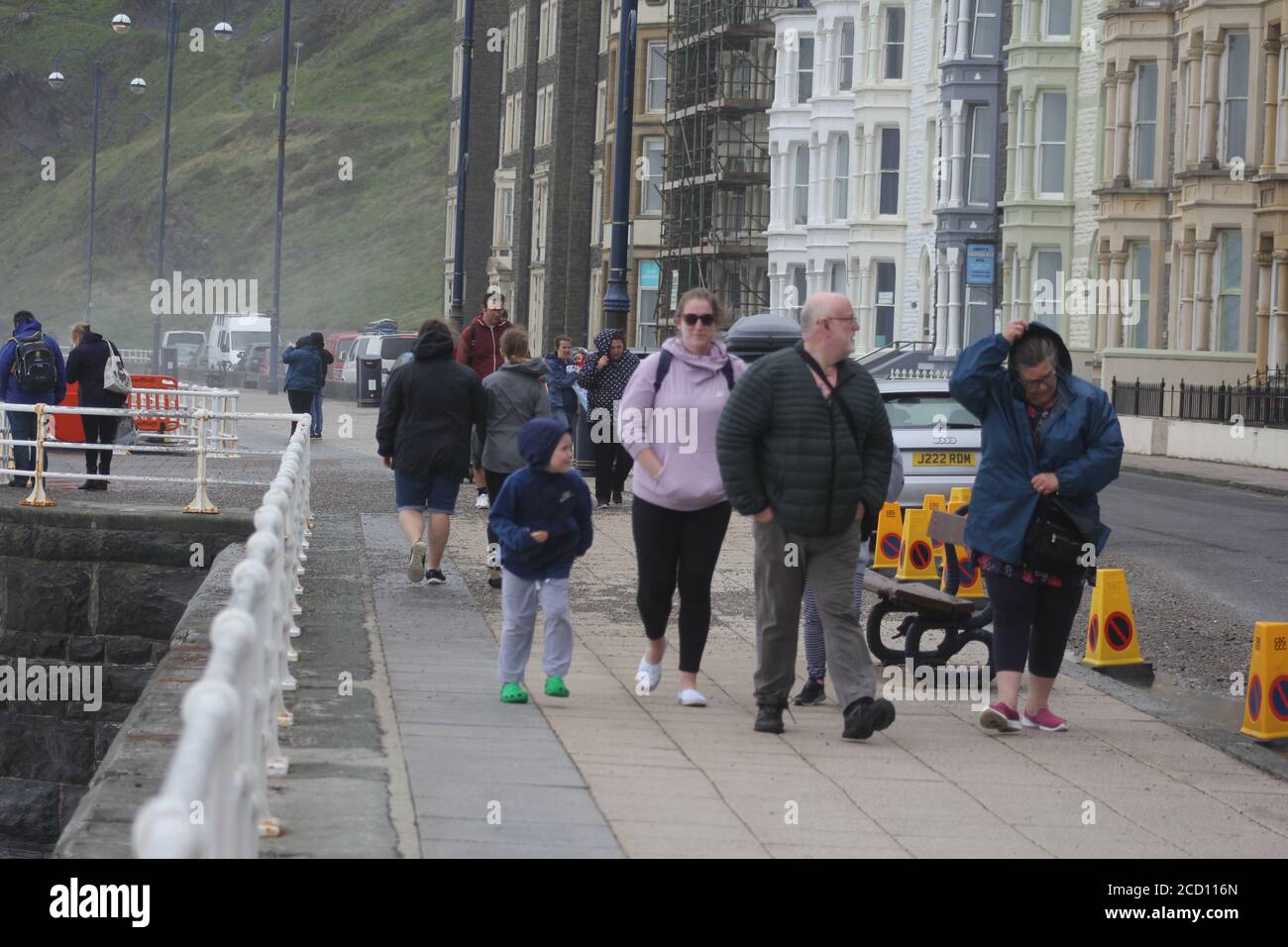 Aberystwyth Wales UK Weather 25 agosto 2020 : forti piogge e venti di Gale Force battter regioni costiere del Galles, forti venti guidare in enormi onde che sconfinano contro le difese marine di Aberystwyth. I vacanzieri coraggiosi venti di forza gale durante una passeggiata pomeridiana tempesta lungo la passeggiata, Credit: mike davies/Alamy Live News Foto Stock