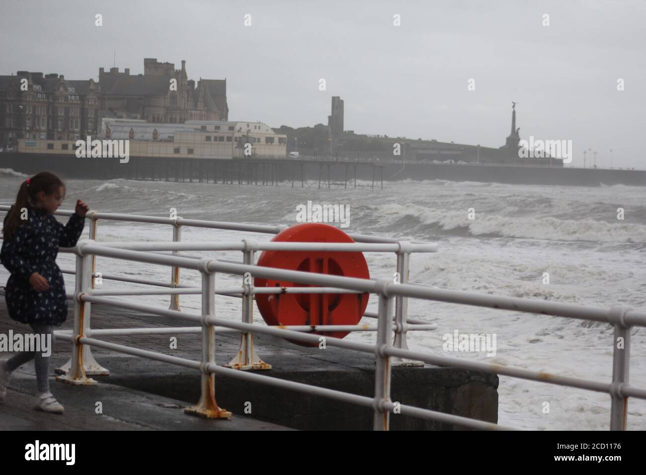 Aberystwyth Wales UK Weather 25 agosto 2020 : forti piogge e venti di Gale Force battter regioni costiere del Galles, forti venti guidare in enormi onde che sconfinano contro le difese marine di Aberystwyth. I vacanzieri coraggiosi venti di forza gale durante una passeggiata pomeridiana tempesta lungo la passeggiata, Credit: mike davies/Alamy Live News Foto Stock