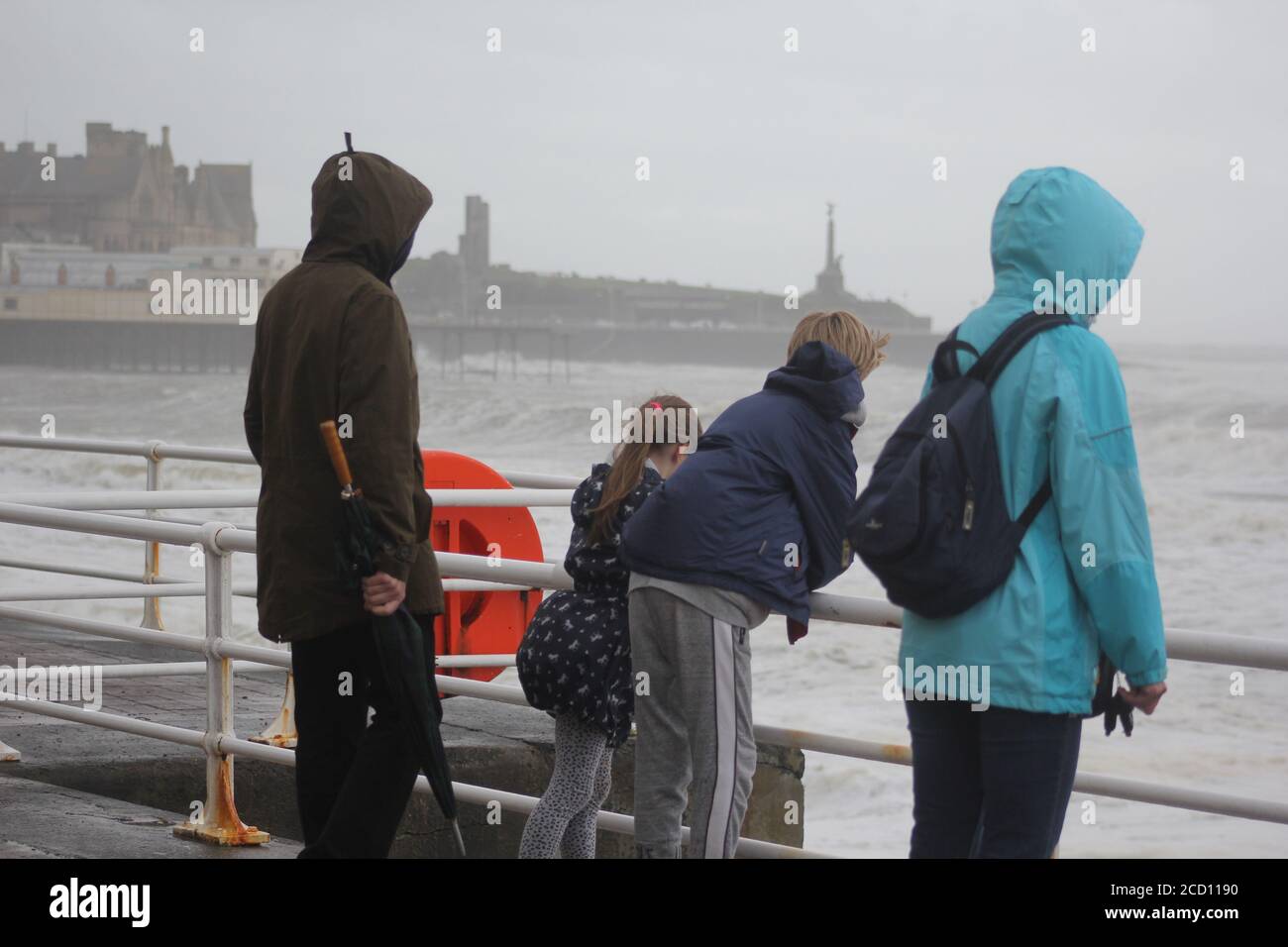 Aberystwyth Wales UK Weather 25 agosto 2020 : forti piogge e venti di Gale Force battter regioni costiere del Galles, forti venti guidare in enormi onde che sconfinano contro le difese marine di Aberystwyth. I vacanzieri coraggiosi venti di forza gale durante una passeggiata pomeridiana tempesta lungo la passeggiata, Credit: mike davies/Alamy Live News Foto Stock