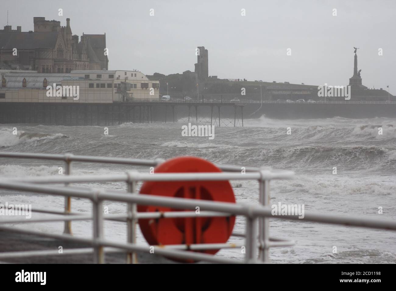 Aberystwyth Wales UK Weather 25 agosto 2020 : forti piogge e venti di Gale Force battter regioni costiere del Galles, forti venti guidare in enormi onde che sconfinano contro le difese marine di Aberystwyth. I vacanzieri coraggiosi venti di forza gale durante una passeggiata pomeridiana tempesta lungo la passeggiata, Credit: mike davies/Alamy Live News Foto Stock