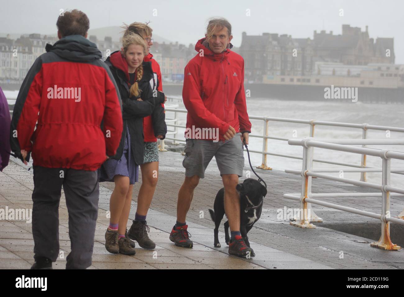 Aberystwyth Wales UK Weather 25 agosto 2020 : forti piogge e venti di Gale Force battter regioni costiere del Galles, forti venti guidare in enormi onde che sconfinano contro le difese marine di Aberystwyth. I vacanzieri coraggiosi venti di forza gale durante una passeggiata pomeridiana tempesta lungo la passeggiata, Credit: mike davies/Alamy Live News Foto Stock