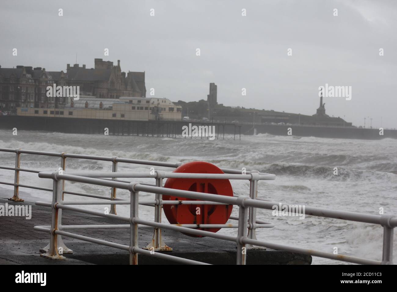 Aberystwyth Wales UK Weather 25 agosto 2020 : forti piogge e venti di Gale Force battter regioni costiere del Galles, forti venti guidare in enormi onde che sconfinano contro le difese marine di Aberystwyth. I vacanzieri coraggiosi venti di forza gale durante una passeggiata pomeridiana tempesta lungo la passeggiata, Credit: mike davies/Alamy Live News Foto Stock