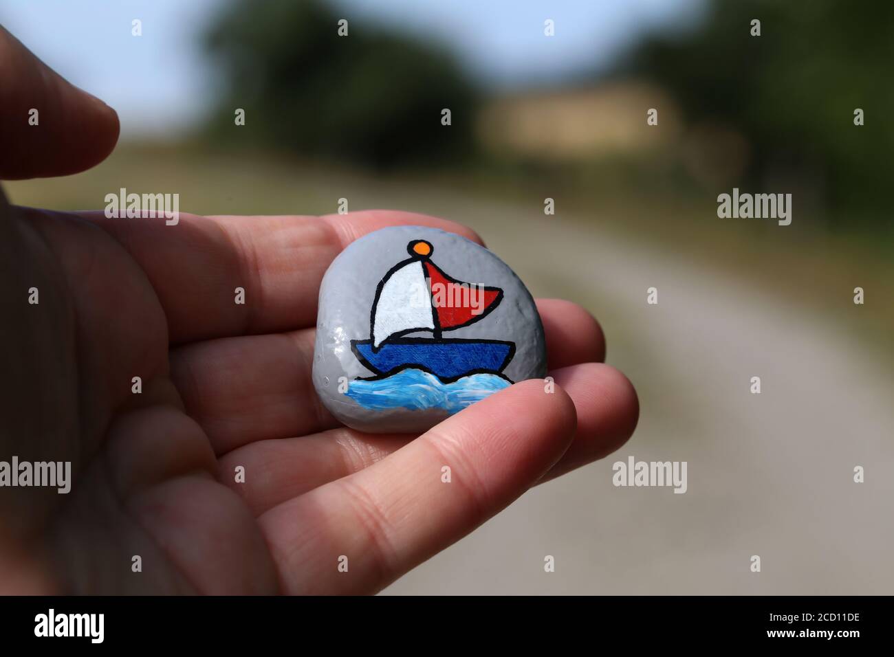 Primo piano di un uomo che tiene una pietra dipinta a sinistra sul sentiero Foto Stock