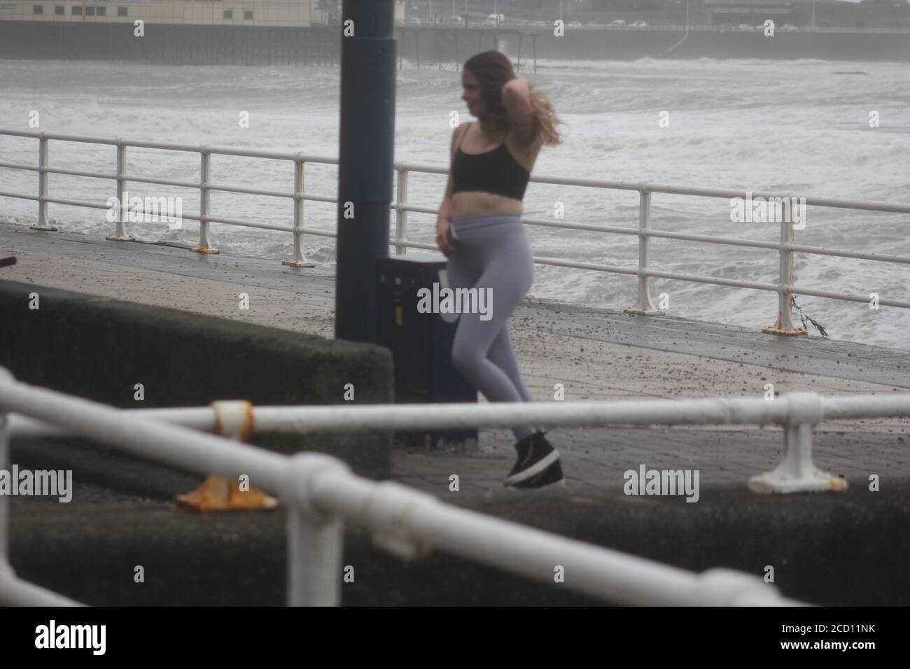 Aberystwyth Wales UK Weather 25 agosto 2020 : forti piogge e venti di Gale Force battter regioni costiere del Galles, forti venti guidare in enormi onde che sconfinano contro le difese marine di Aberystwyth. I vacanzieri coraggiosi venti di forza gale durante una passeggiata pomeridiana tempesta lungo la passeggiata, Credit: mike davies/Alamy Live News Foto Stock