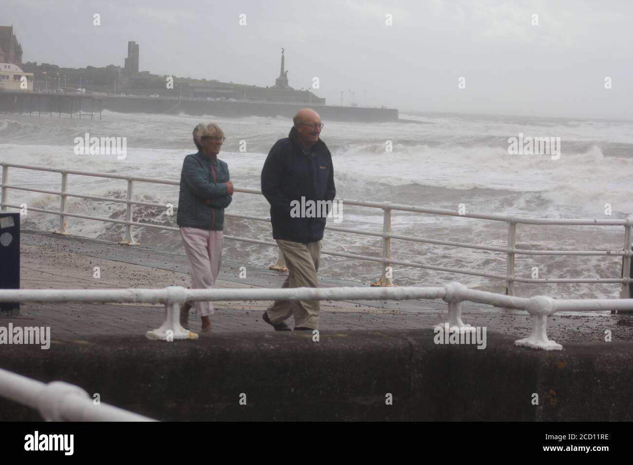 Aberystwyth Wales UK Weather 25 agosto 2020 : forti piogge e venti di Gale Force battter regioni costiere del Galles, forti venti guidare in enormi onde che sconfinano contro le difese marine di Aberystwyth. I vacanzieri coraggiosi venti di forza gale durante una passeggiata pomeridiana tempesta lungo la passeggiata, Credit: mike davies/Alamy Live News Foto Stock