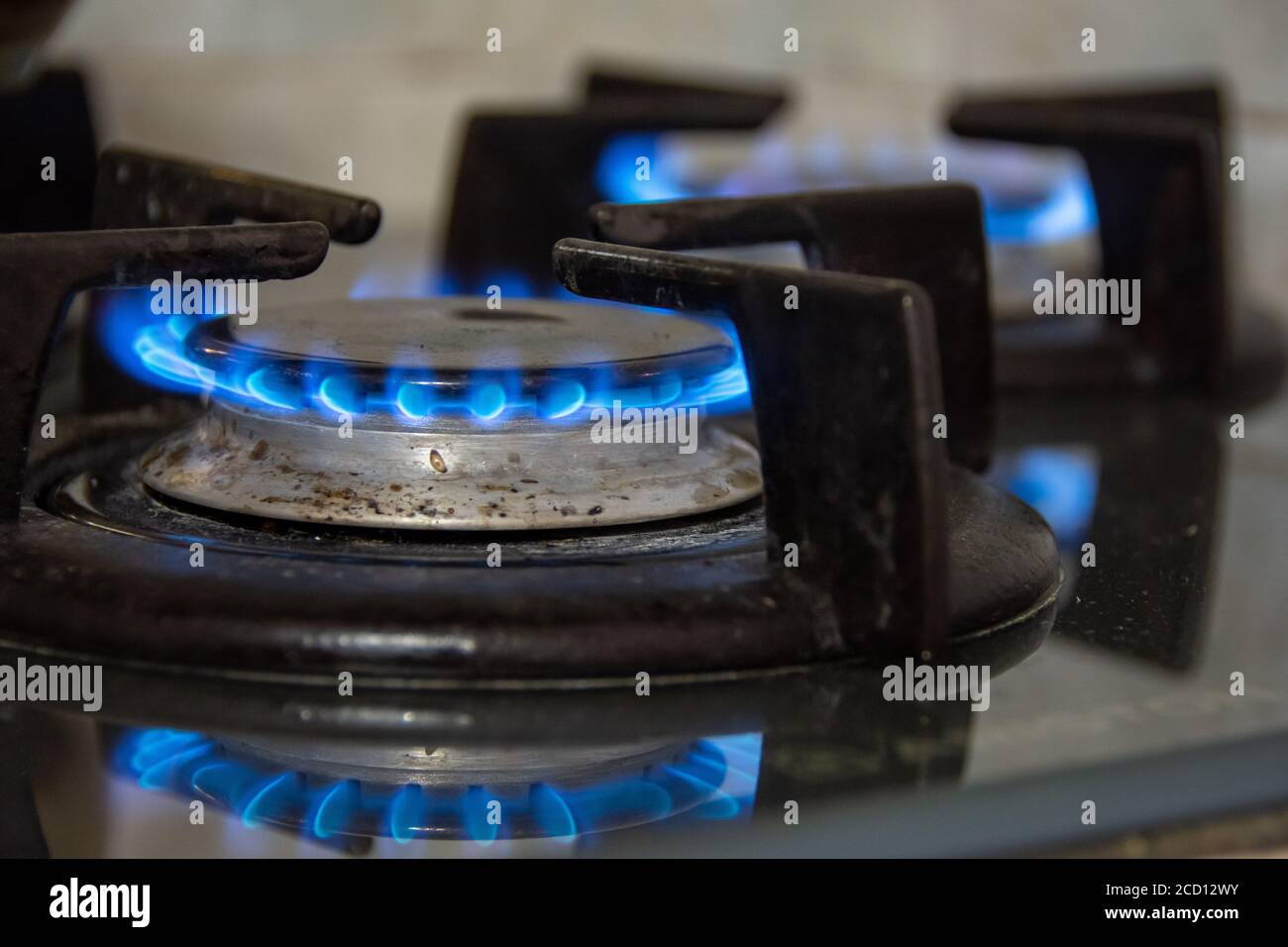 Gas che brucia con fiamme blu su un fornello a gas Foto Stock