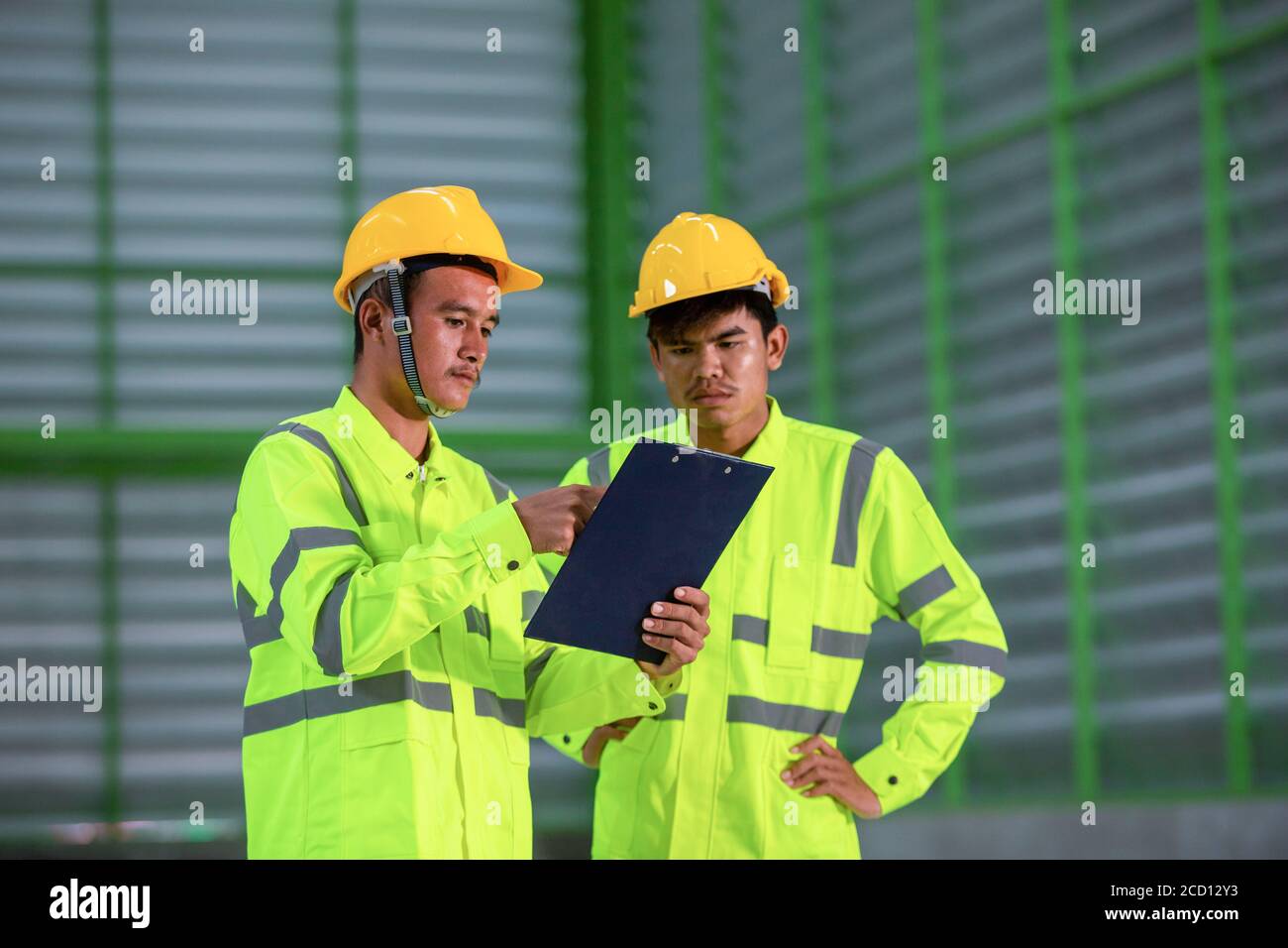 Ingegnere industriale asiatico in un piano di giacca di sicurezza con casco rigido Lavorare con i processi dei lavoratori del magazzino in fabbrica Foto Stock