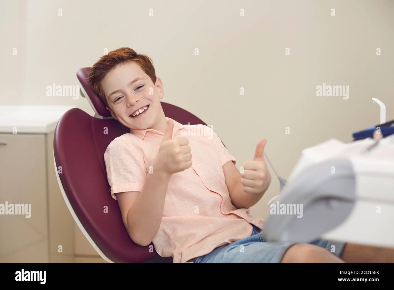 Clinica dentale. Paziente felice del ragazzo che mostra i pollici in su segno durante la visita del dentista Foto Stock