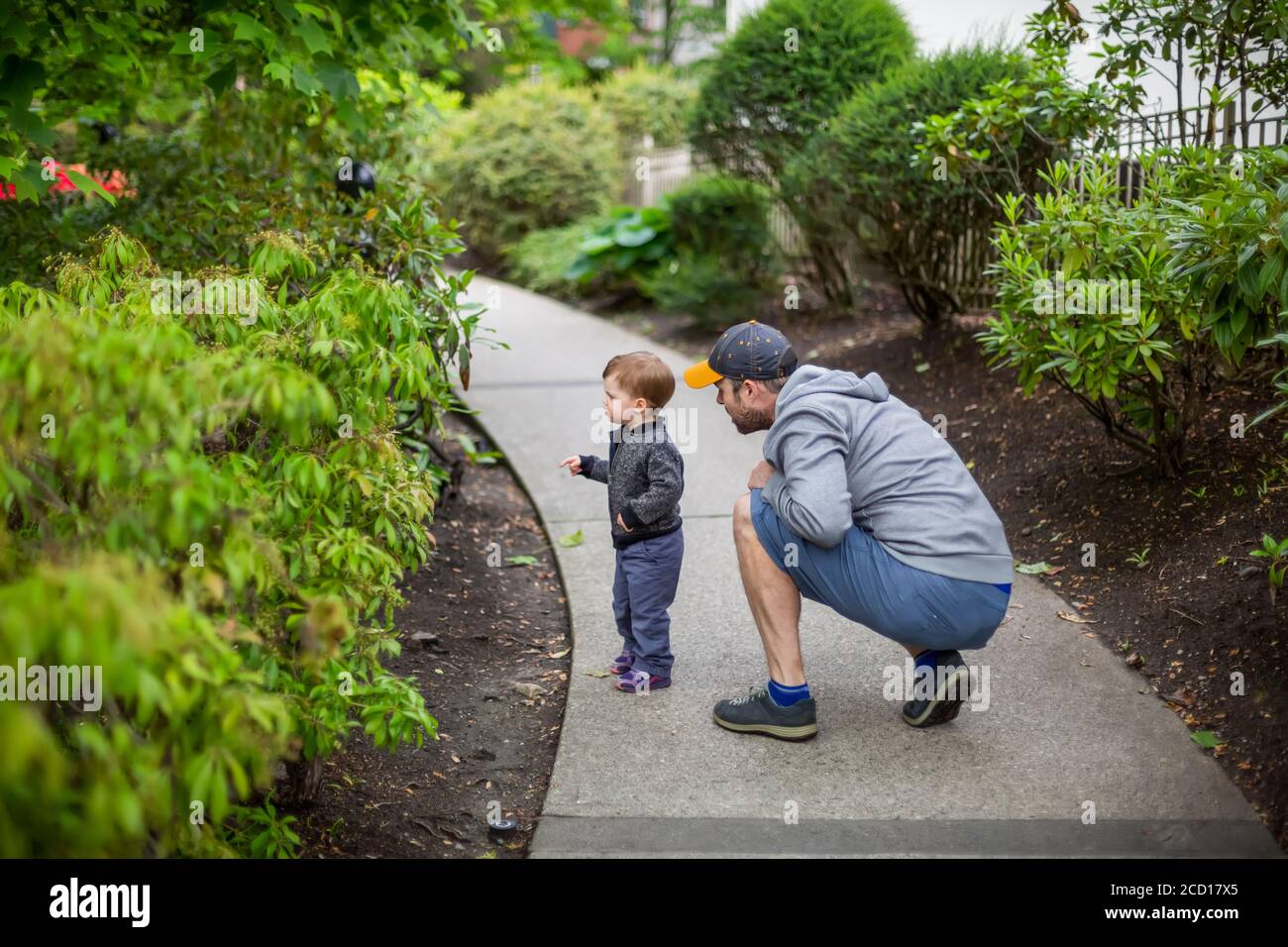Un padre si accovacciò vicino alla sua giovane figlia su un percorso mentre scoprono la natura; Vancouver del Nord, Columbia Britannica, Canada Foto Stock