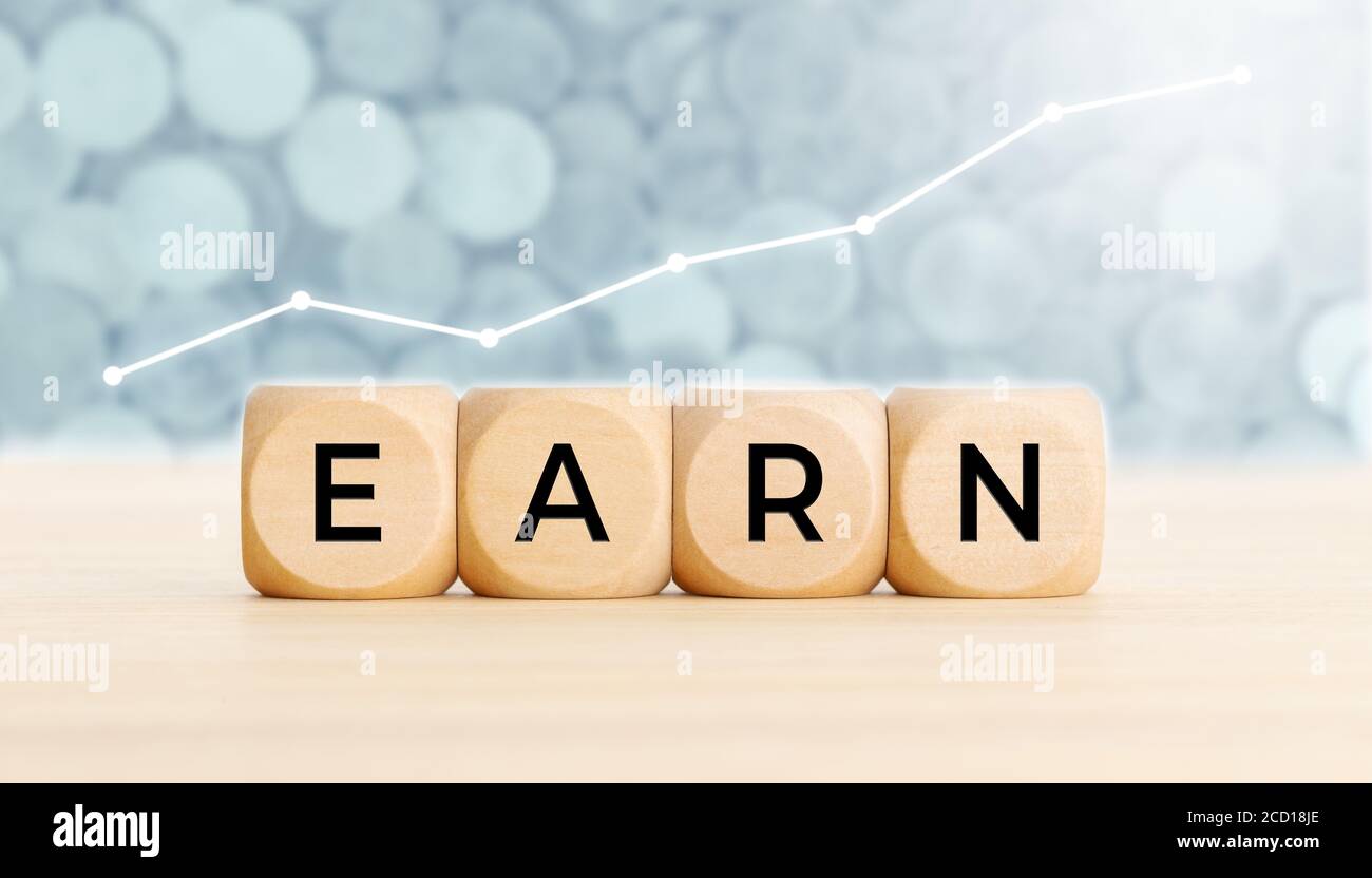 Guadagna il concetto. Blocchi di legno con testo sulla tabella e grafico sullo sfondo. Spazio di copia Foto Stock