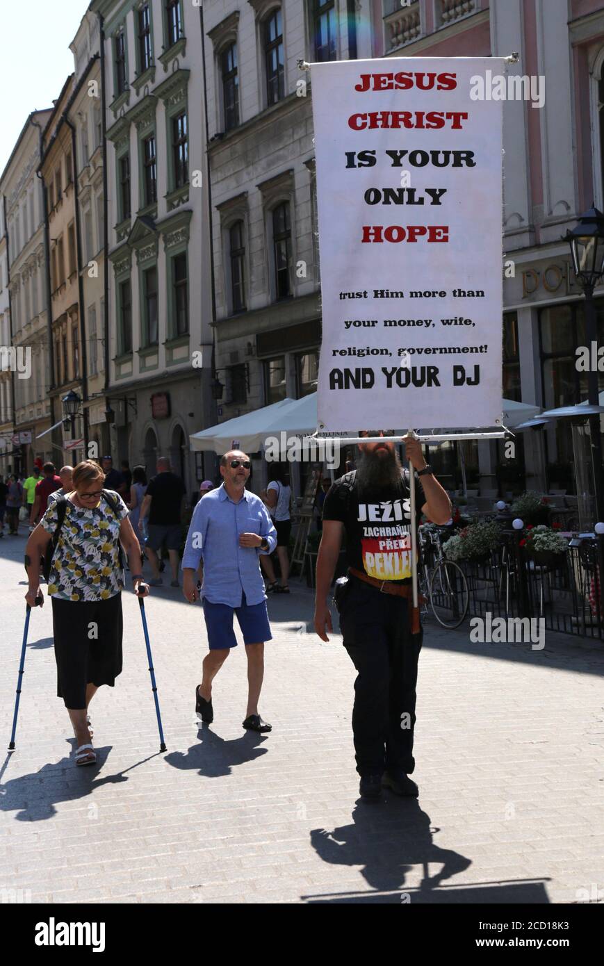 Cracovia. Cracovia. Polonia. Uomo che tiene bandiera religiosa che cammina per la città vecchia. Foto Stock
