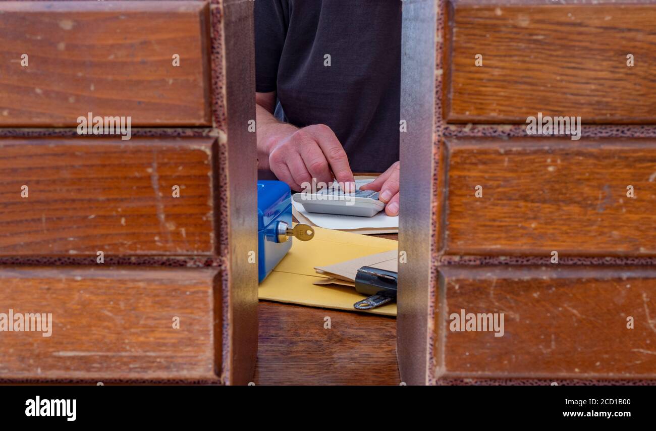 Uomo che usa una calcolatrice su una scrivania ordinata sullo sfondo,  mostrando lo spazio tra due set di piccoli cassetti in primo piano Foto  stock - Alamy