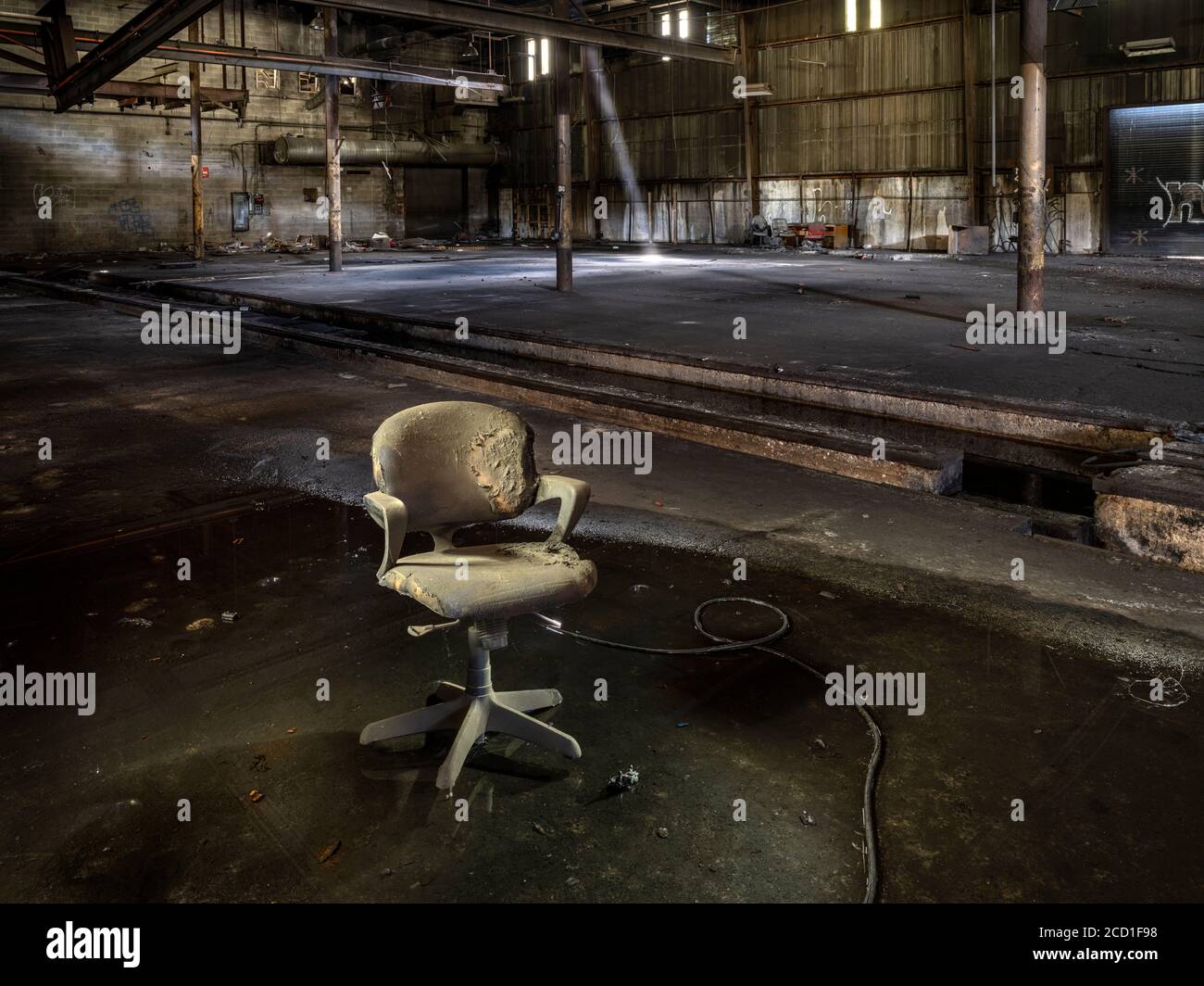 Vecchia sedia sporca seduta in acqua all'interno di una fabbrica industriale abbandonata Foto Stock