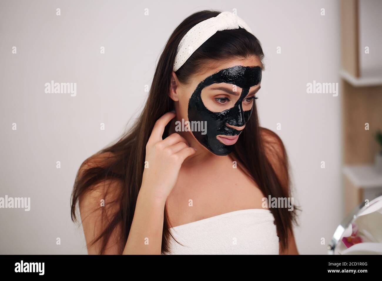 Giovane donna con maschera nera detox di carbonio sul viso, la ragazza  adolescente si prende cura della pelle oleosa, pulizia dei pori. Salone di  bellezza. Cura della pelle Foto stock - Alamy