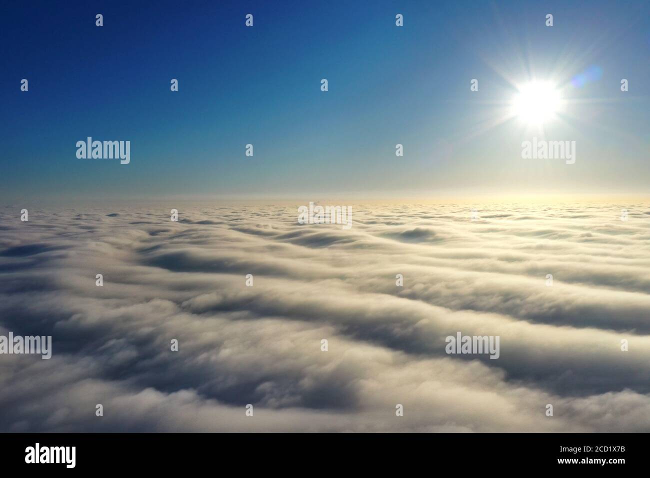 Fotografia aerea, sole luminoso sopra l'orizzonte e sopra dense nuvole grigie in un cielo blu scuro. Foto Stock