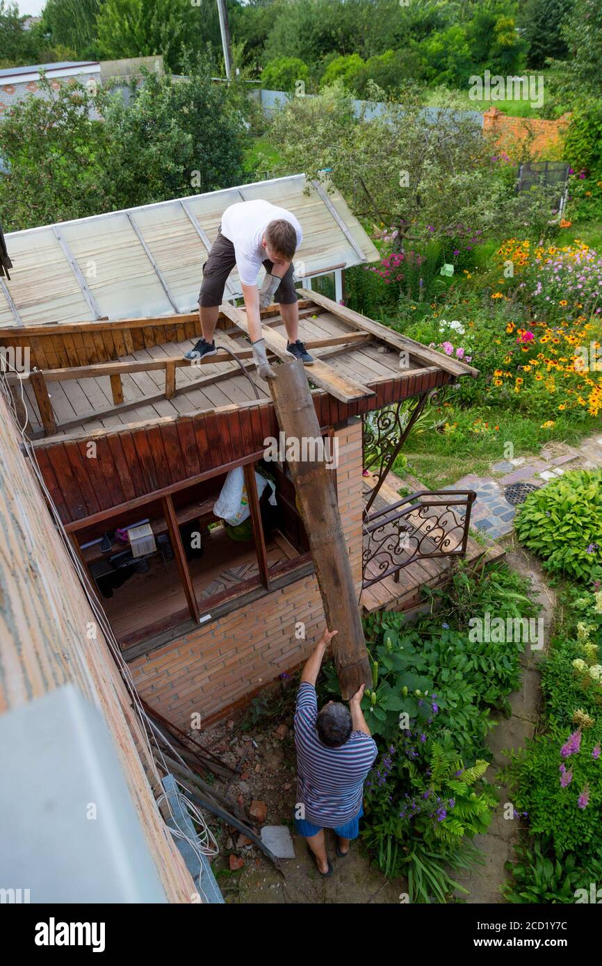 smontaggio del tetto. Il lavoratore rimuove le vecchie tavole Foto Stock