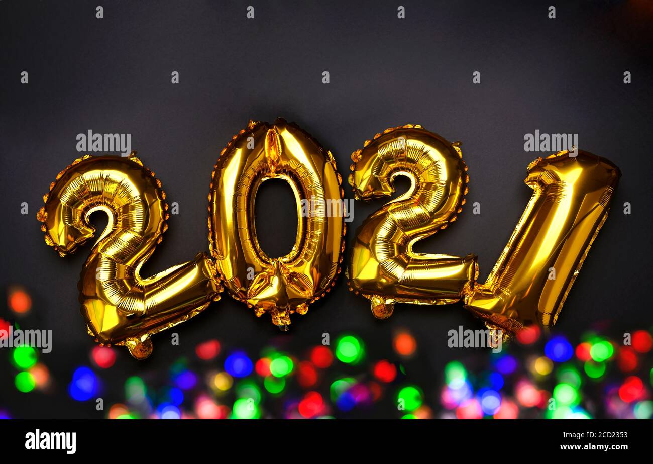 Felice celebrazione del nuovo anno 2021. Palloncini d'oro e d'argento con numero 2021 e bokeh multicolore su sfondo nero. Cartoline e poster. Foto di alta qualità Foto Stock