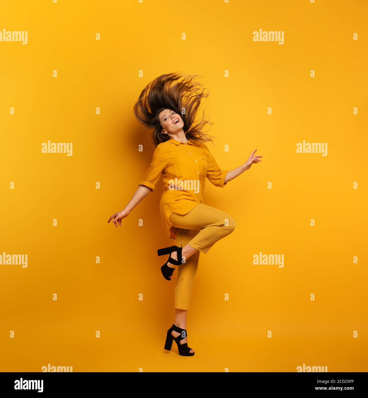 Bruna ragazza con un vestito giallo salta. Concetto di moda e shopping con espressione gioiosa Foto Stock