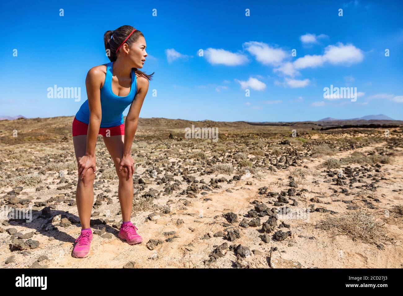 Trail runner donna stanca respirando duro durante l'esercizio cardio ultra running esaurito su gara difficile corsa. Giovane atleta asiatico in estate nel deserto Foto Stock