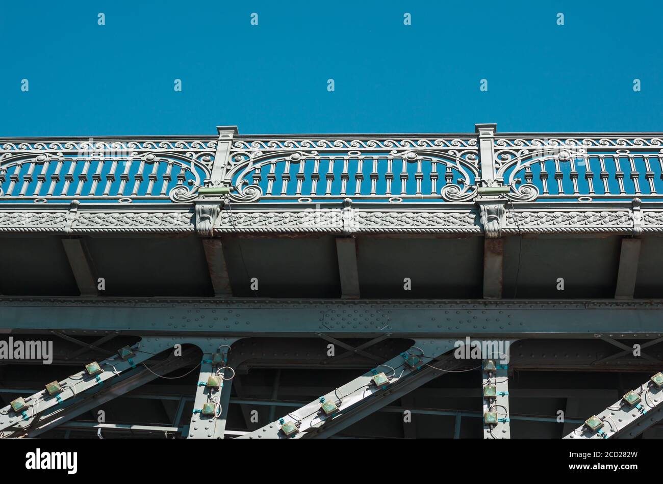 Recinzione ornata di vecchio ponte metallico forgiato contro il cielo blu ripresa dal basso Foto Stock