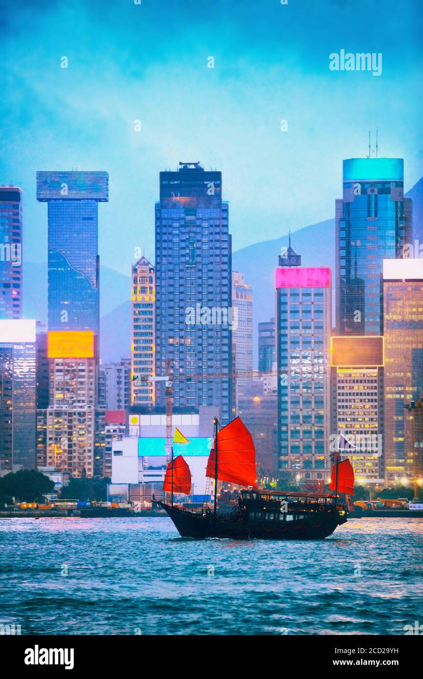 Vista dello skyline di Hong Kong al tramonto del Victoria Harbour dal lato di Tsim Sha Tsui con cartelli al neon illuminati di notte. Vista sulla vita notturna con barca spazzatura Foto Stock