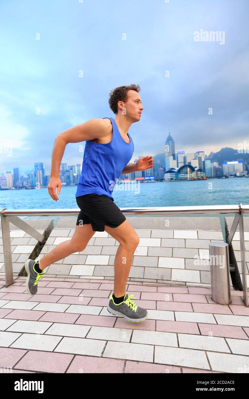 Corridore attivo di sport che fa jogging nella via della città del porto di Hong Kong vivere un sano stile di vita urbano allenarsi al mattino. Uomo di espatriati caucasici Foto Stock