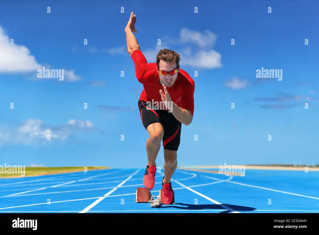 Atleta di runner che inizia a correre all'inizio della pista su piste da corsa blu all'aperto e allo stadio dei fiel. Sprinter in gara. Sport e. Foto Stock
