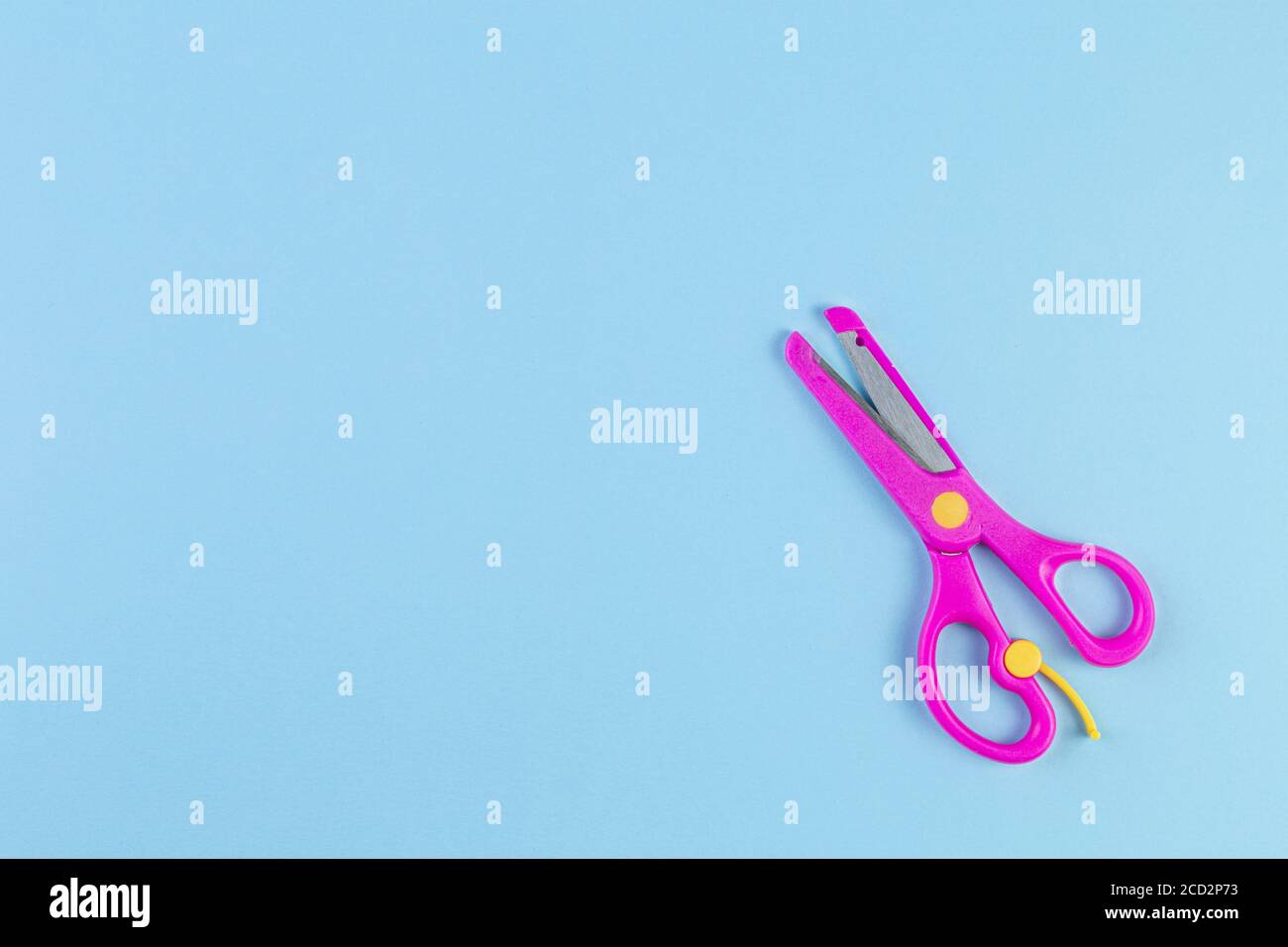 Foto minimalista delle forbici rosa per bambini su sfondo blu. Concetto di ritorno a scuola con cancelleria. Con spazio di copia, modello per testo o disegno. Foto Stock