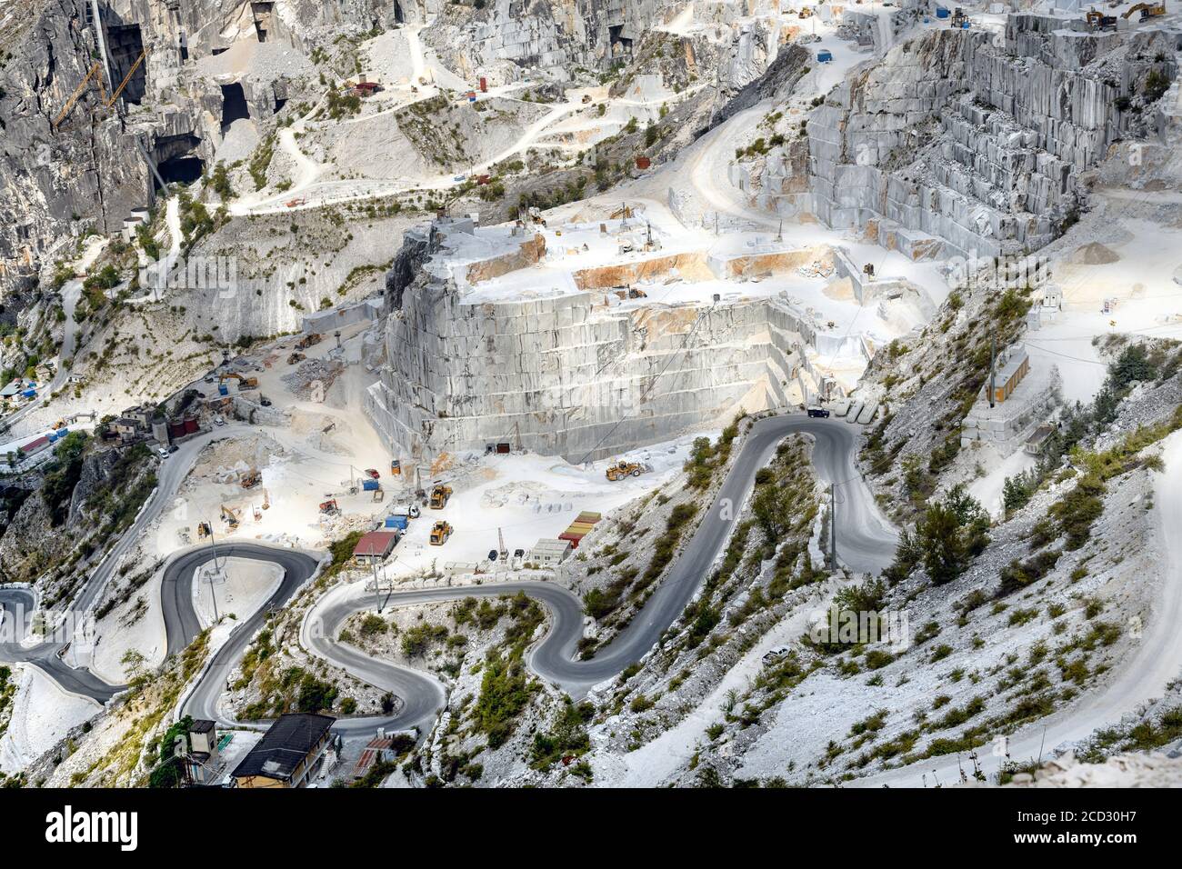 Vista panoramica delle cave di marmo di Carrara in una montagna ripida valle che mostra l'estrazione a getto aperto e una strada tortuosa in Toscana Italia Foto Stock