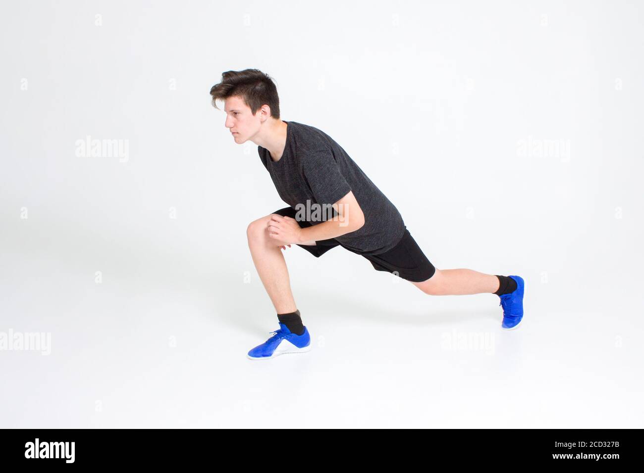 Un ragazzo in una t-shirt sportiva nera e shorts, sneakers blu, treni Foto Stock