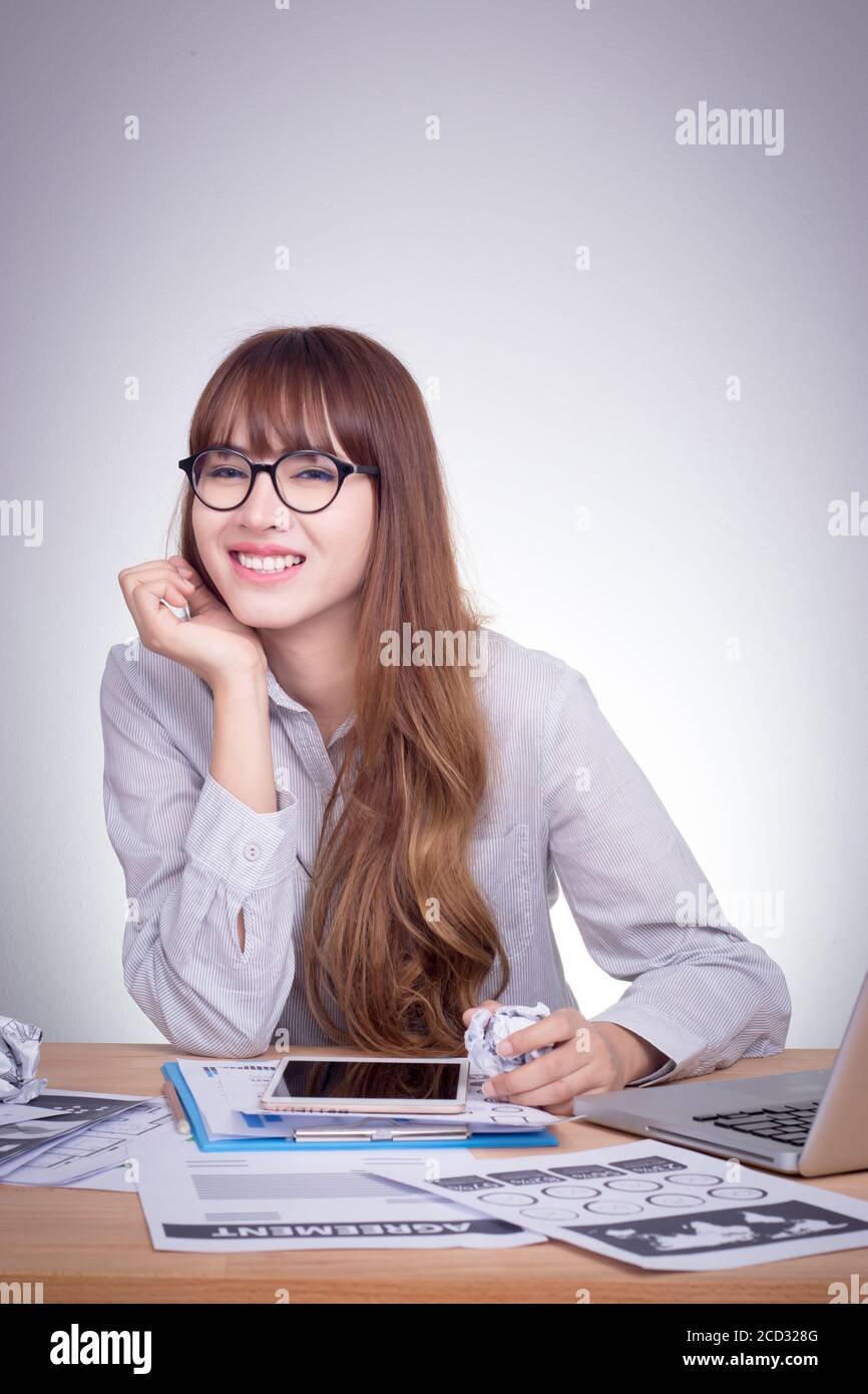 Felice donna asiatica d'affari appoggiata sul tavolo in ufficio con faccia sorridente Foto Stock