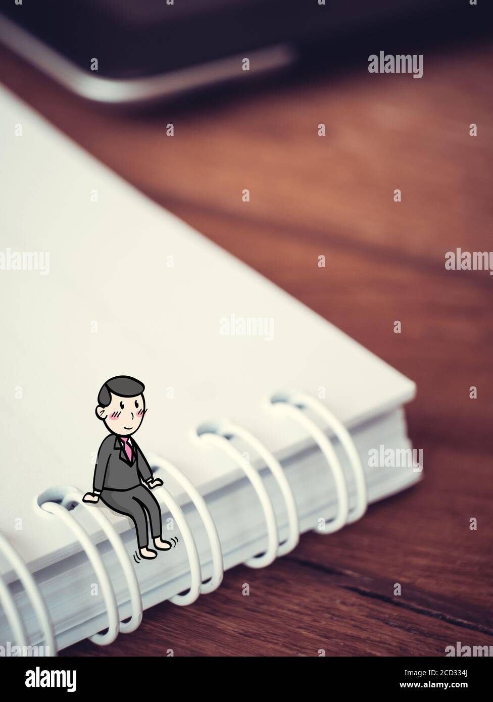 Concetto felice di uomo d'affari : uomo di cartoon piccolo siedono sul libro di nota in vestito che si rompono con il volto smiley Foto Stock