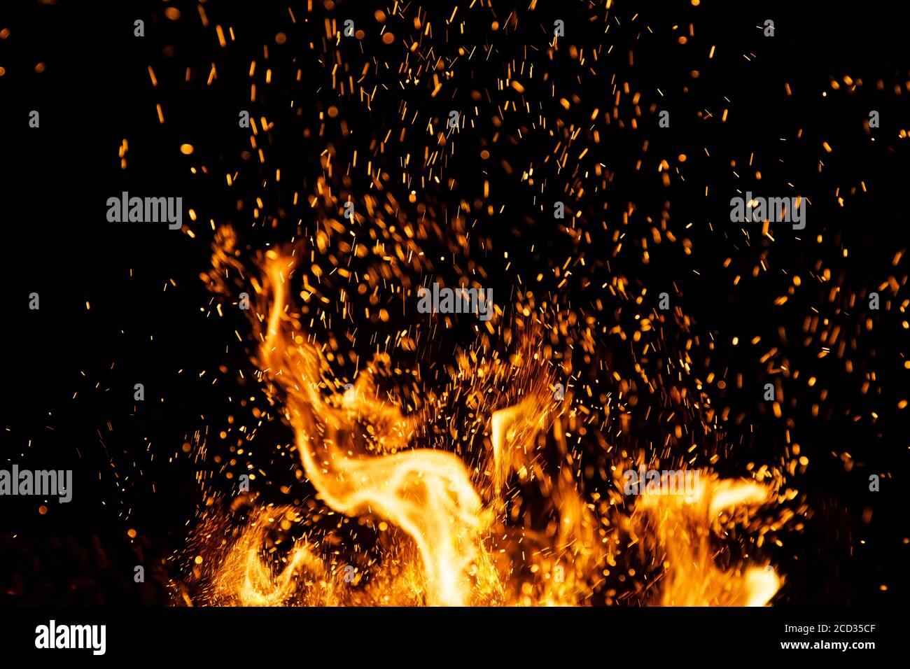 Il fuoco scintilla particelle con fiamme isolate su sfondo nero. Foto Stock