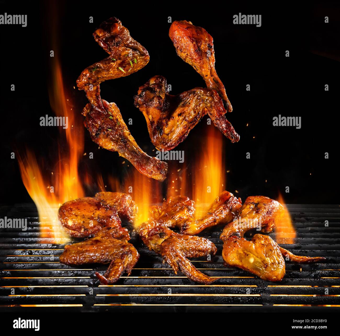 Pezzi volanti di carne di pollo alla griglia con fiamme di fuoco. Isolato su sfondo nero. Barbecue e grill. Molto immagine ad alta risoluzione Foto Stock