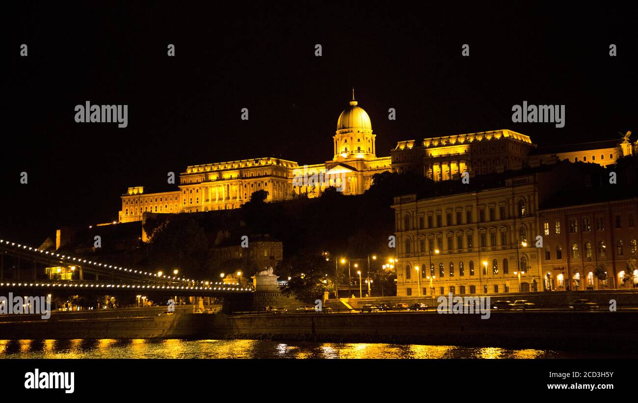 Europa dell'Est, Ungheria, Budapest, Palazzo reale (Kiralyi palota) di notte, il Danubio in primo piano Foto Stock