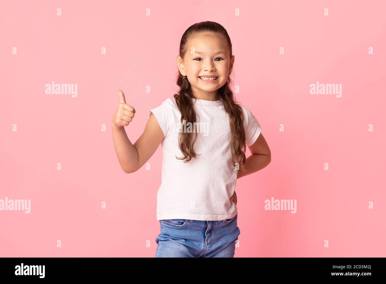 Ragazza asiatica che mostra il pollice e sorridente Foto Stock