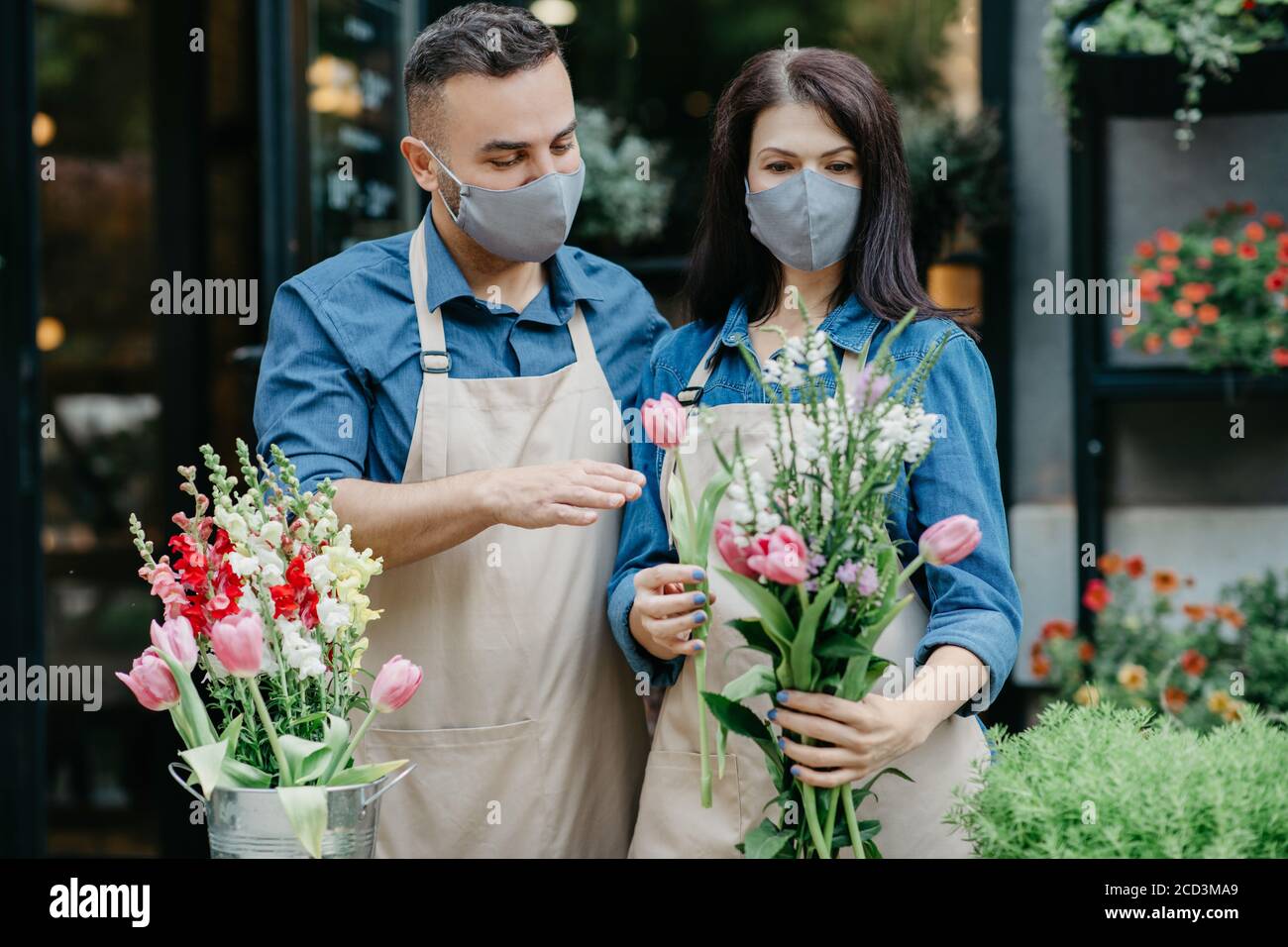 Bouquet design in negozio di fiori. Giovane uomo e donna lavorano con le piante per il cliente Foto Stock