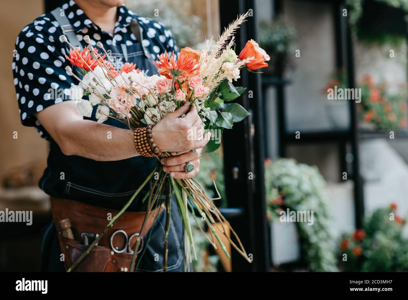 Composizione floreale in mani di professionisti. Donna in grembiule, con attrezzi fa bouquet in negozio di fiori Foto Stock