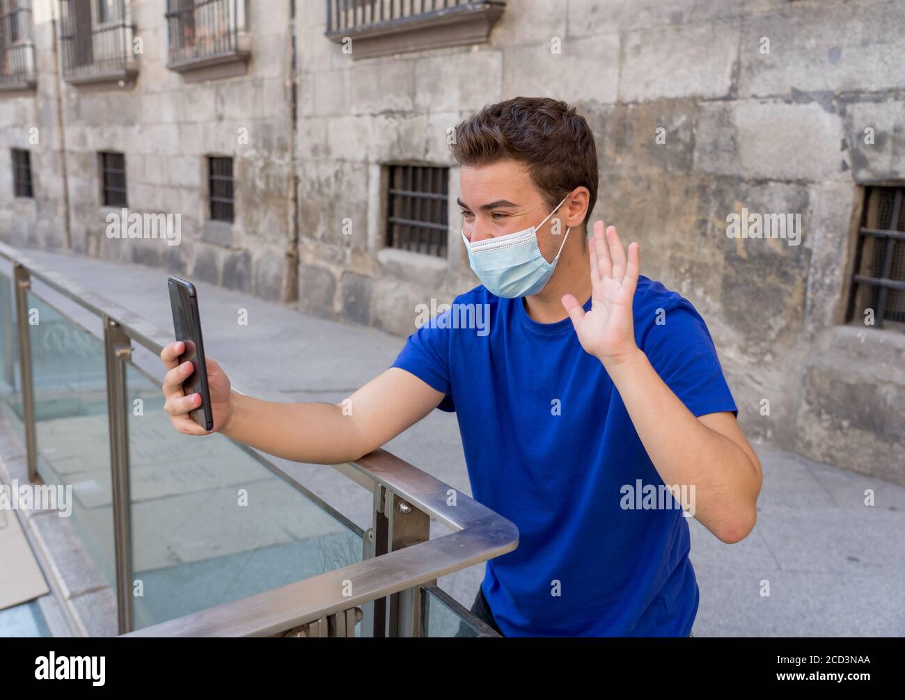 COVID-19 focolaio. Giovane uomo in città strada indossando maschera chirurgica protettiva e utilizzando il telefono cellulare videochiamare amici e familiari. Rimani connesso i Foto Stock