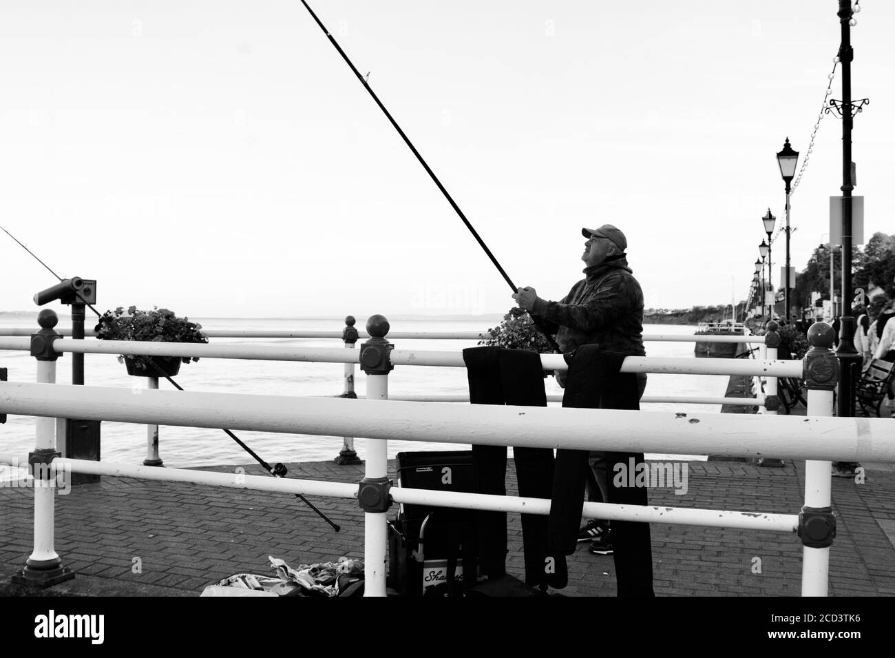 Foto in bianco e nero di pescatori speranzosi di una cattura in alta marea sulla spianata Penarth. La passeggiata è popolare tra la gente del posto e i turisti. Foto Stock