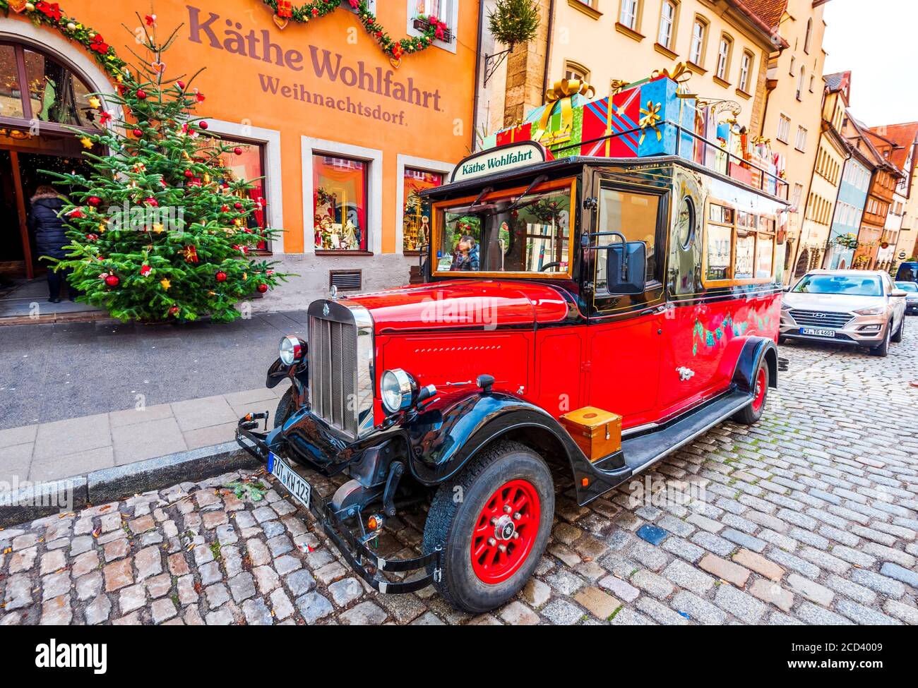 Rothenburg ob der Tauber, Germania - Dicembre 2018: Auto rossa retrò nei pressi di un negozio che vende regali di Natale tradizionali nella città vecchia medievale in Baviera Foto Stock