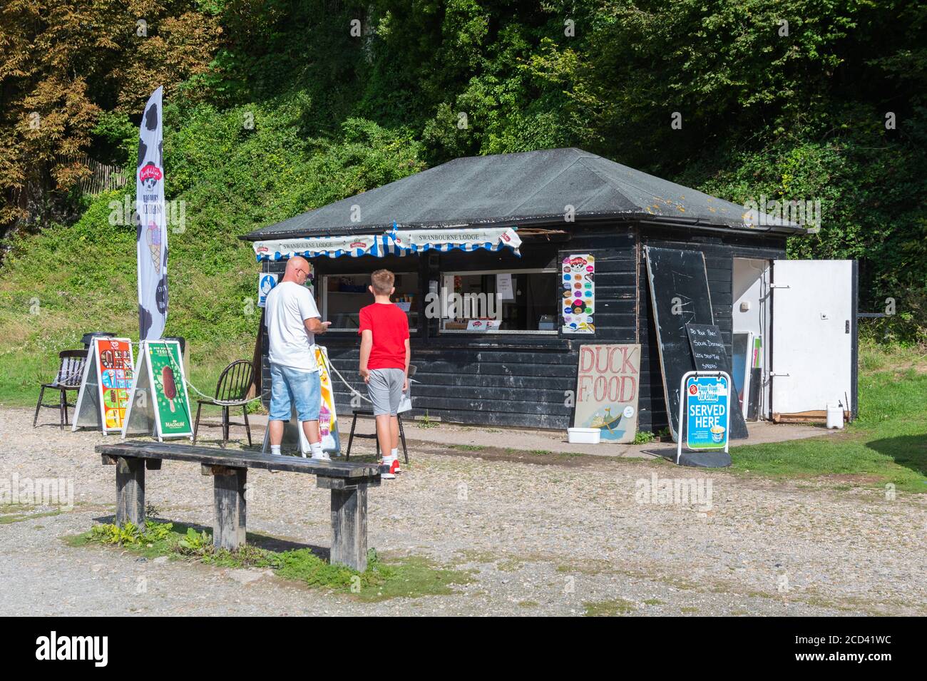 Uomini e bambini adulti cercano di acquistare bevande rinfrescanti da un caffè all'aperto in estate al lago Swanbourne, Arundel, West Sussex, Inghilterra, Regno Unito. Foto Stock