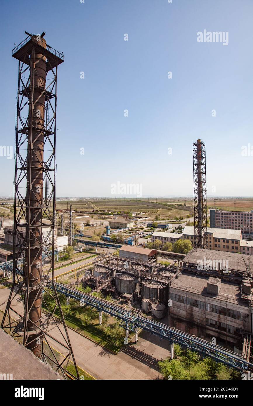 Vecchi edifici di fabbrica di metallurgia sovietica e camini arrugginiti e serbatoi di stoccaggio su cielo blu. Vista aerea. Taraz città. Foto Stock