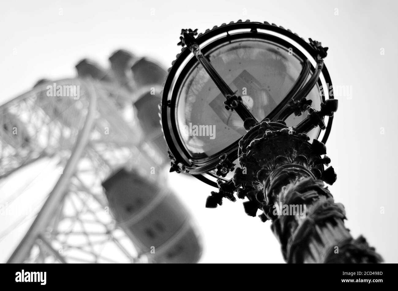 Immagine in scala di grigi di una lampada da strada con una ruota panoramica sullo sfondo sfocato Foto Stock