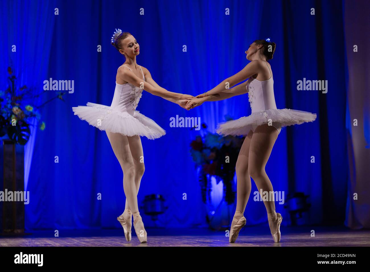 Ballerina giovane donna in un tutu bianco danza su palcoscenico in un teatro su sfondo blu Foto Stock