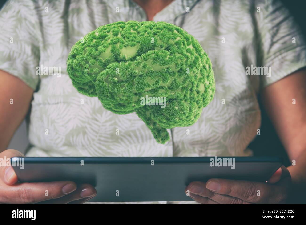 Concetto di eco-friendly, pensare verde e altre idee ecologiche. Cervello umano con erba verde che cresce su di esso che galleggia sopra la tavoletta è tenuto da Foto Stock
